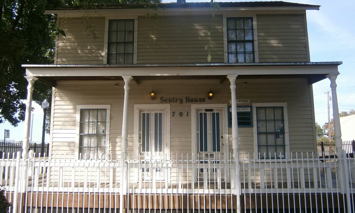 White two-story wood duplex with a front porch and picket fence in Alkali Flat