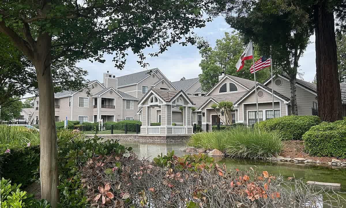 Two-story apartment buildings beside a lake and gardens in Sacramento's Pocket area